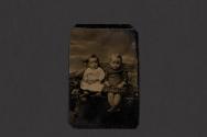 [Two small children posing seated in studio]
