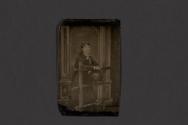 [Woman posing with fence and hat in studio]