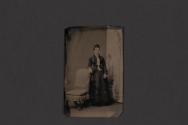 [Woman posing next to chair in studio]