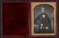 [Man holding daguerreotype portrait of woman]