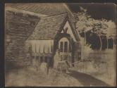 [Man sitting by entry to stone building]