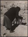 [Woman putting wreath on grave]