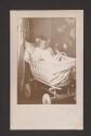 [Baby in wicker bassinet]