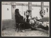 Elderly woman sitting beside grave