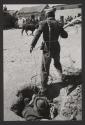Men feeding rope into hole, Peru