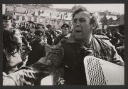 British soldiers near a barricade. In the foreground, a soldier bleeding from his nose. On the left, a pretty Irish girl, shouting protests, is pushed away by a soldier, North Ireland