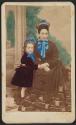 [Woman seated, posed with child at side]