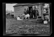 George Eastman and friends in front of cabin with two dogs, Alaska trip