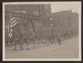 [Snapshot of soldiers and officers holding American flag in parade]