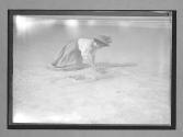 [woman kneeling on beach]