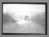 [auto driving down country road]