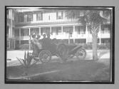 [people in auto in front of hotel]