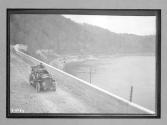 [auto driving by river, railroad track]