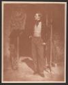 [Young man in jacket and waistcoat, standing in profile]