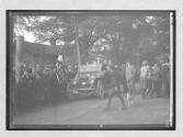 [AAA auto in town with spectators]