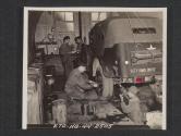 [A section of great importance to a signal company is the motor section. Seen here are T/4 Ward Mumford, Wayne, Mich., and T/5 Jesse Weatherford, Big Sandy, Tenn. In the background, M.SGT Cleave Cozart, Glen Daniels, W. VA., confers with T/5 Thomas Moir, Joliet, ILL., about some parts to be ordered.  5th Sig Co, 5th Inf Div, Braynsford, County Down, Northern Ireland.]