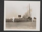 [While German ammunition trucks that were hit by American tanks, burn, infantrymen keep advancing on the road to Angers, France.]