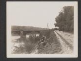 [ Infantry dig in along the banks of the Seine River to protect the flanks of the US Army Engineers who are building a pontoon bridge across the river. The bridge in the background that was destroyed during the action around the town of Vulaines-Sur-Seine, France.]
