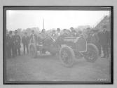[auto racer surrounded by men at track]