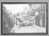 [auto racers in auto surrounded by spectators in town]