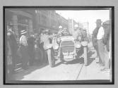 [auto racers in auto surrounded by spectators in town "Maxwell"]