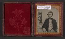 [Botanist seated next to notebook and plant]