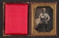 [Seated man with surveyor tools and pistol]
