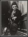 [Woman upright going up stairs with broom, mop, and bucket.]