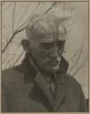 [Old man in coat with tree branches in background on the set of the film "Native Land."]
