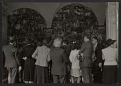 [Group of tourists crowded in front of Diego Rivera's mural, "The History of Mexico: Tierra y Libertad," in Mexico City]