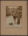 [Woman holding camera with horse and dog]