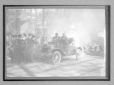 [auto tourists in town with spectators]