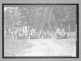 [autos lined up on country road "#53, #55, #63"]