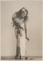 [Woman reaching down to pick up a flower]