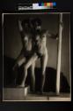 [Two female nudes on steps with pole]