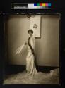 [Fashion photo, model with Lanvin fur-trimmed evening gown holding feather fan]