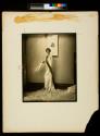 [Fashion photo, model with Lanvin fur-trimmed evening gown holding feather fan]