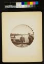 [Man and boy standing near housboat in the water, Thousand Islands]