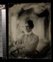 [Young soldier wearing smoking cap, seated with arms folded]