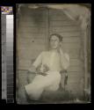 [Soldier in undershirt and white pants, seated holding cane]