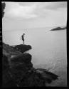 [Figure on rocks by water]