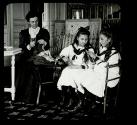 [Woman teaching two girls how to knit]