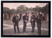 [Four soldiers in dress uniform standing in a courtyard]