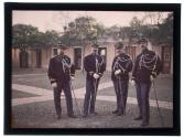 [Four soldiers in dress uniform standing in a courtyard]