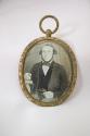 [Oval pendant with daguerreotype of man with hand on a book]