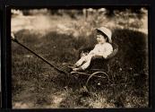 [Small child in wicker cart]