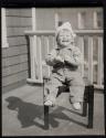 [Child on stool on porch]