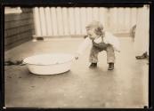 [Child on porch with basin]