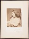 [Young girl posing with arms resting on table]