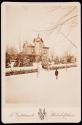 [Winter scene of a man facing a large residence]